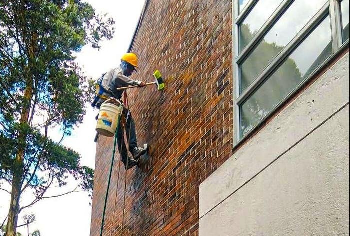 Operario suspendido trabajando sobre una fachada en ladrillo